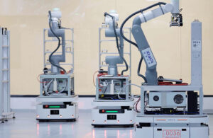 Three white and grey mobile manipulators built by ABB and XtalPi.