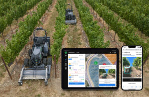 An image showing two black tractors making their way between row crops, with a tablet and phone in the corner showing the Agtonomy interface.