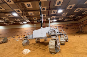 The Airbus Mars Rover, a white boxy robot with six wheels and a tall sensor rising from the center of the robot.