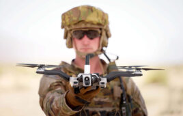 A solder in camo and sunglasses looking into the camera and holding Red Cat's Black Widow drone.