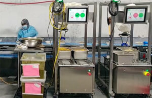 two chef robotics pods sit side by side on a food production like, scooping servings onto food trays.