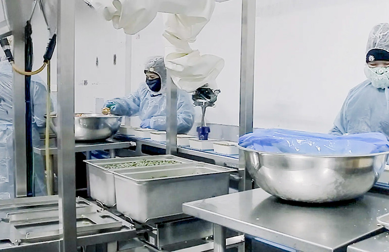 Chef robotics robot scoops food into meal trays.