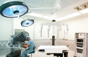 The inside of an operating room with the da Vinci Xi surgical system. A surgeon in blue scrubs sits at the console. Hoag has 10 Intuitive Surgical robots.