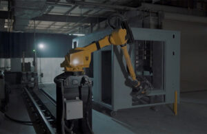 A yellow GrayMatter robot sanding the frame of an emergency vehicle at Life Line.