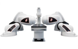 The Stereotaxis Genesis RMN, which features two large, white robotic arms with magnets on each end, sitting in between the arms is a table.