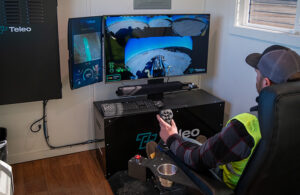 an operator sits at the teleo operations center controlling a remote construction vehicle.