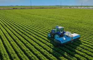 tractor pulls a verdant implement through a field.